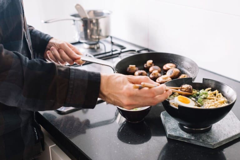 Chef tossing noodles in a pan on the stove