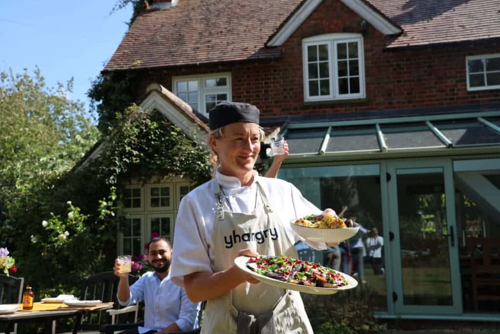 Private chef carrying a platter of food to an outdoor table