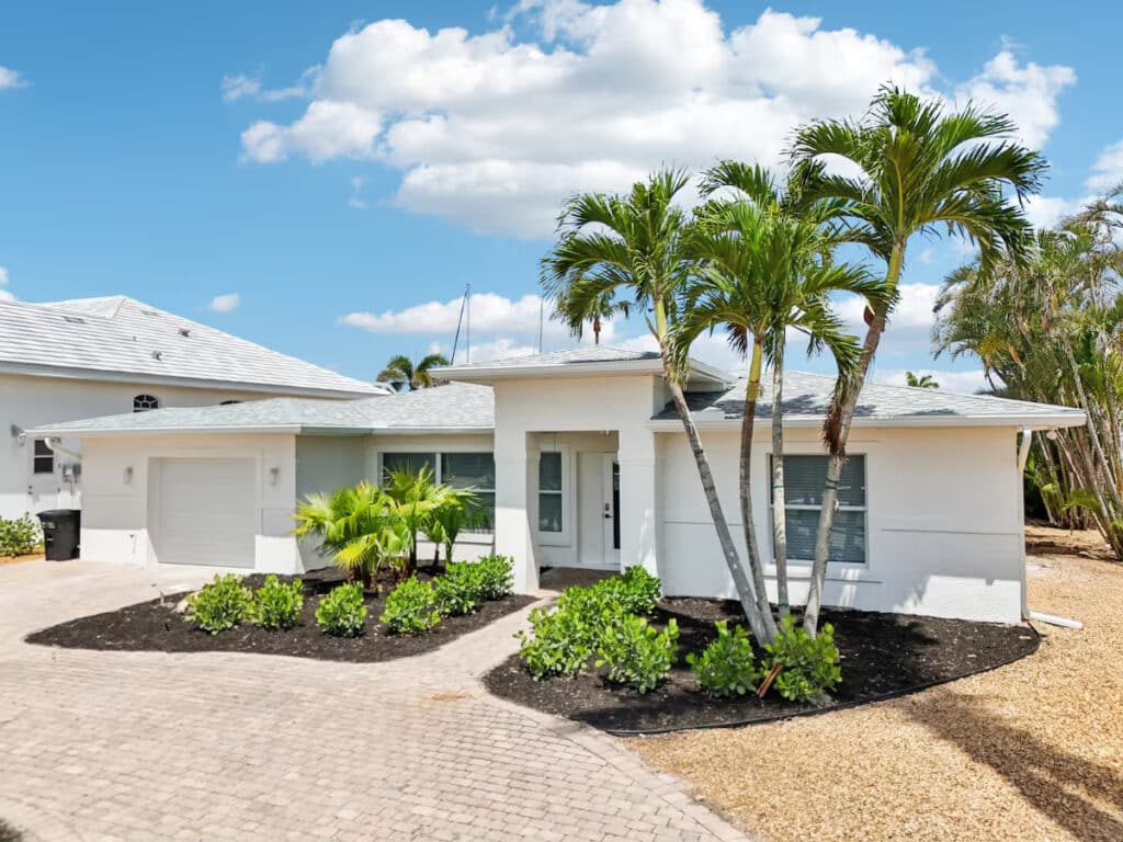 White canal-front vacation home framed by palm trees in Fort Myers Beach, Florida