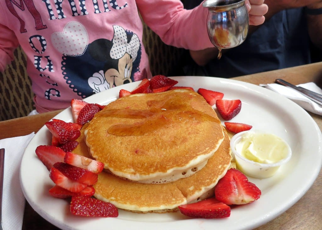 A stack of pancakes topped with fresh strawberries at a breakfast cafe