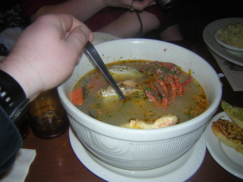 A rustic bowl of seafood stew with shellfish in a tomato saffron broth