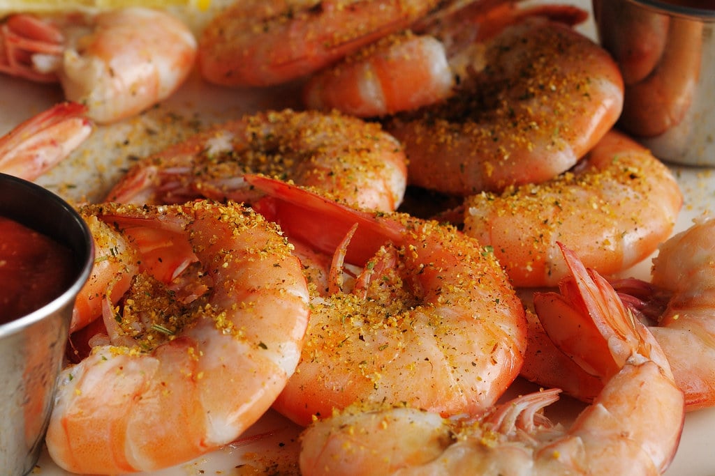 A pile of peel-and-eat shrimp with cocktail sauce at a coastal restaurant