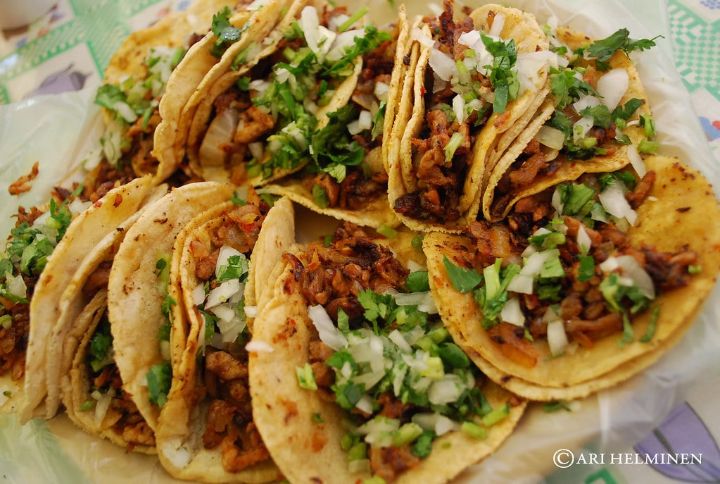 Tacos al pastor with pineapple, cilantro and onion on a plate