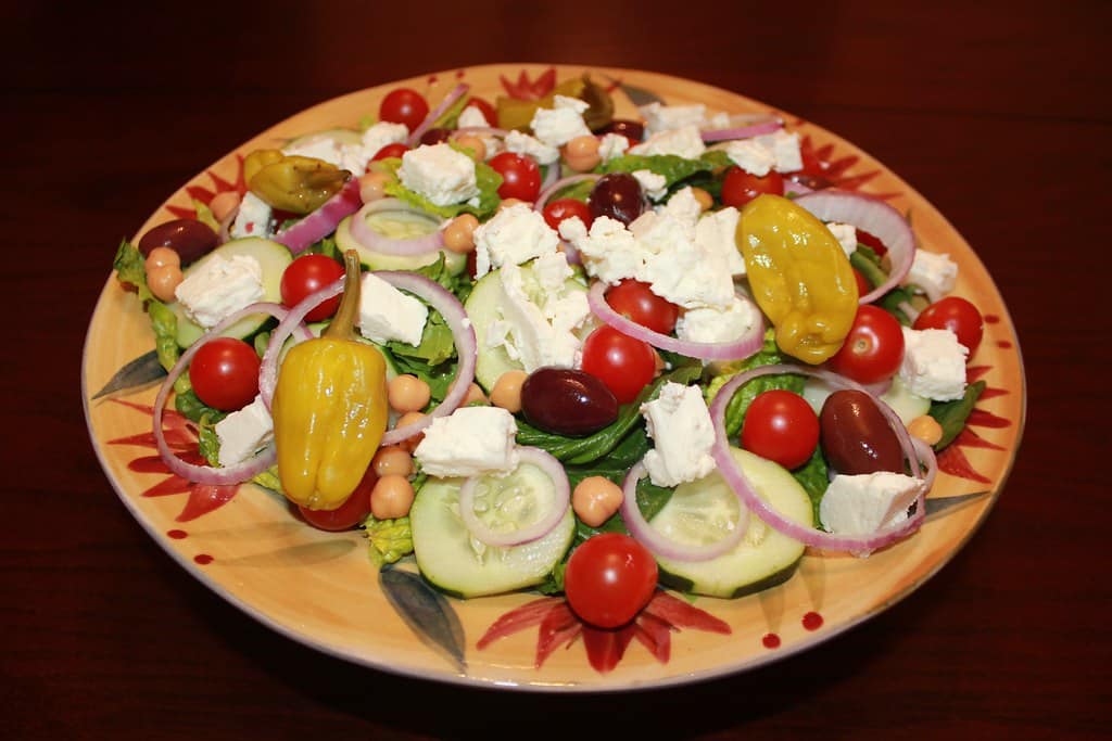 A large Greek salad with feta, olives, tomatoes and cucumber on a plate